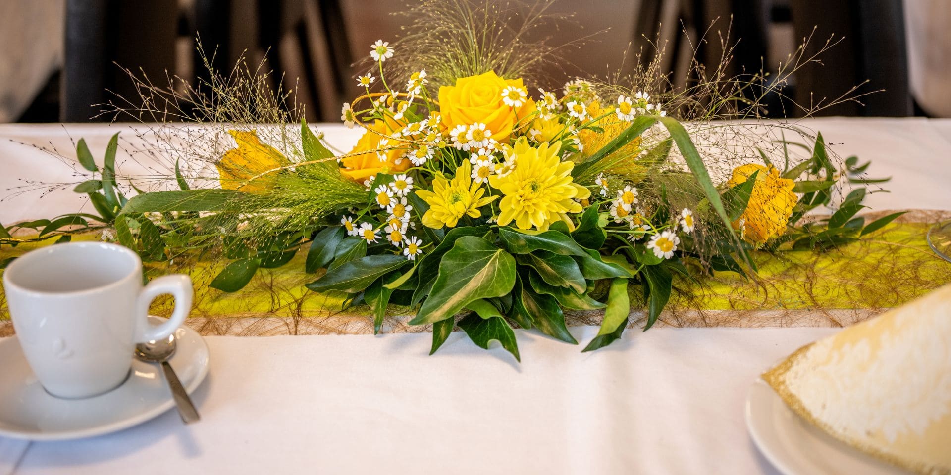 Eine Tasse und gelbe Blumen als Dekoration auf einem TIsch
